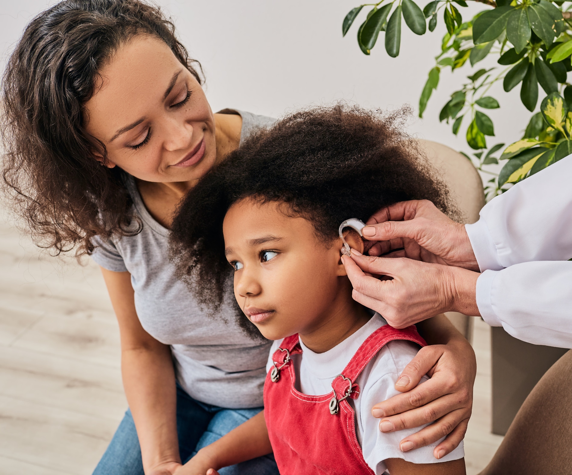 Little girl at hearing aid fitting with her mom.
