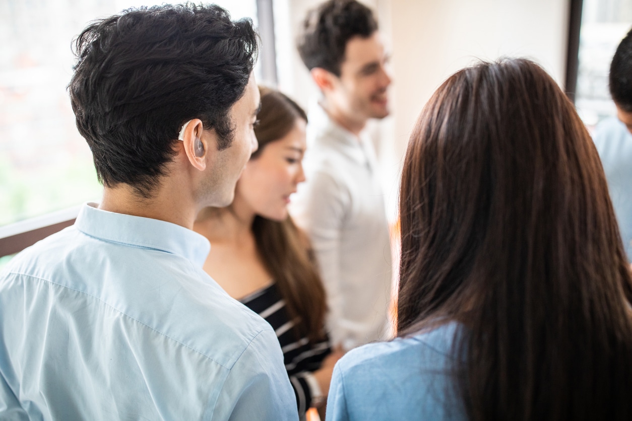 Young man with hearing aids talking in a group of friends.