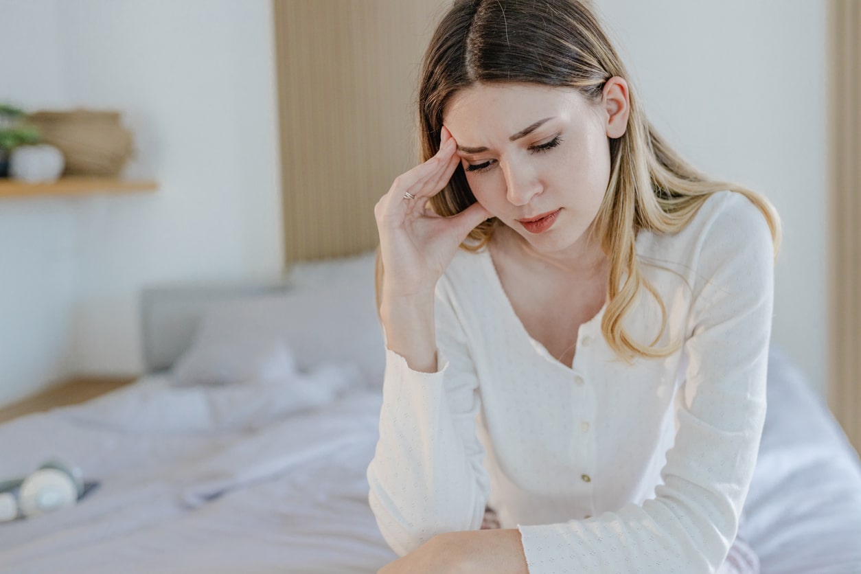 Young woman holding her head struggling with tinnitus.
