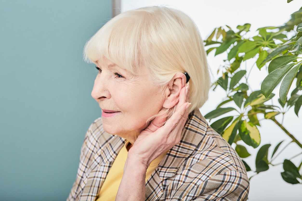 Happy senior woman showing off her hearing aid