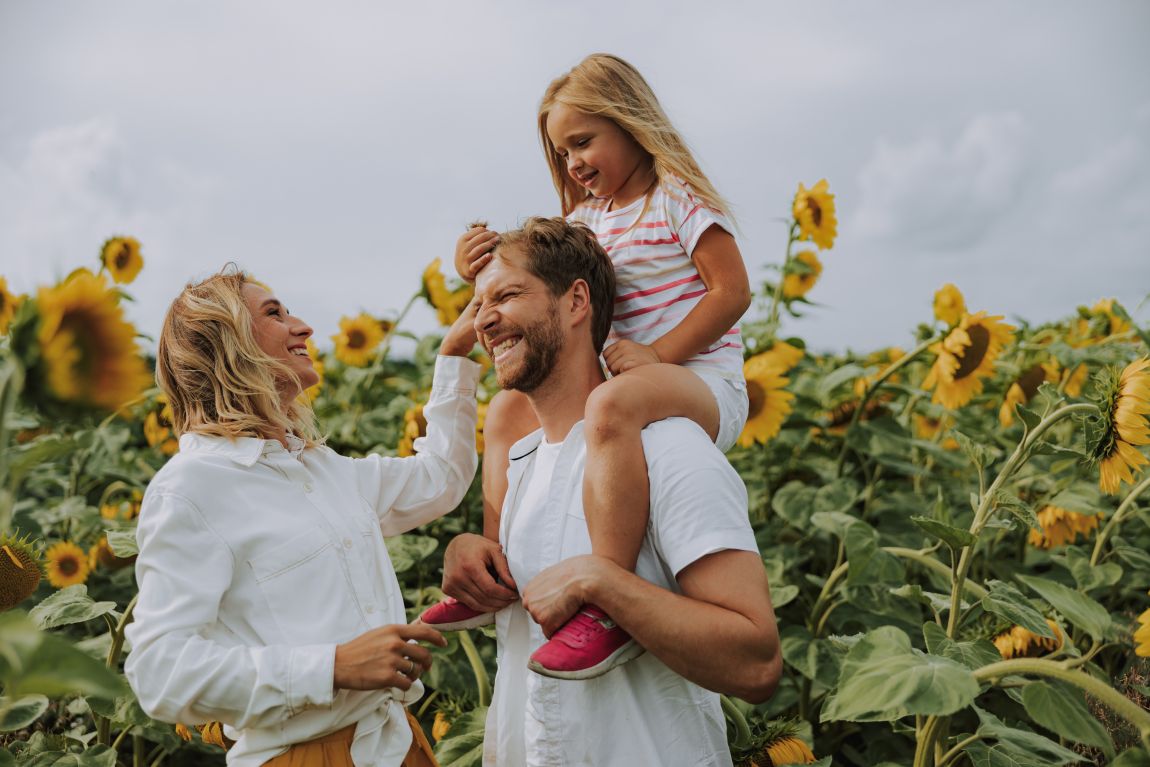 happy family laughing in field of sunflowers
